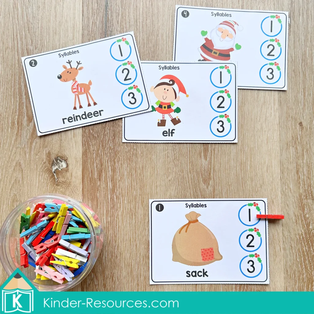 Christmas Literacy Centers for Kindergarten syllable cards for sorting one-, two-, and three-syllable words using clips and holiday-themed pictures.