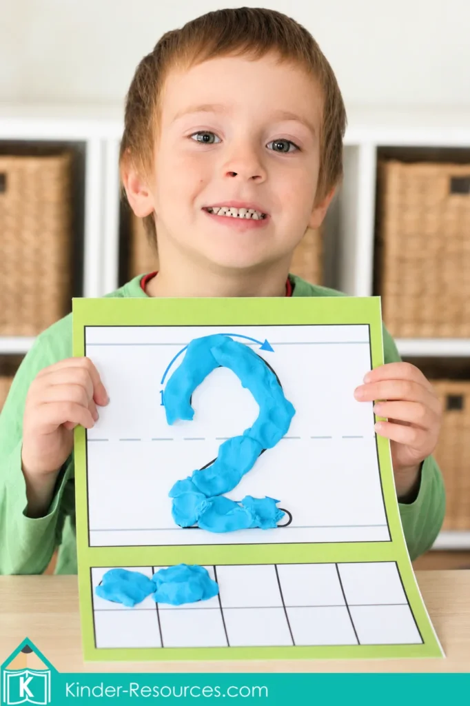 Preschool letter J math activity with a child holding a number 2 play dough mat and two pieces of blue play dough in a ten frame.
