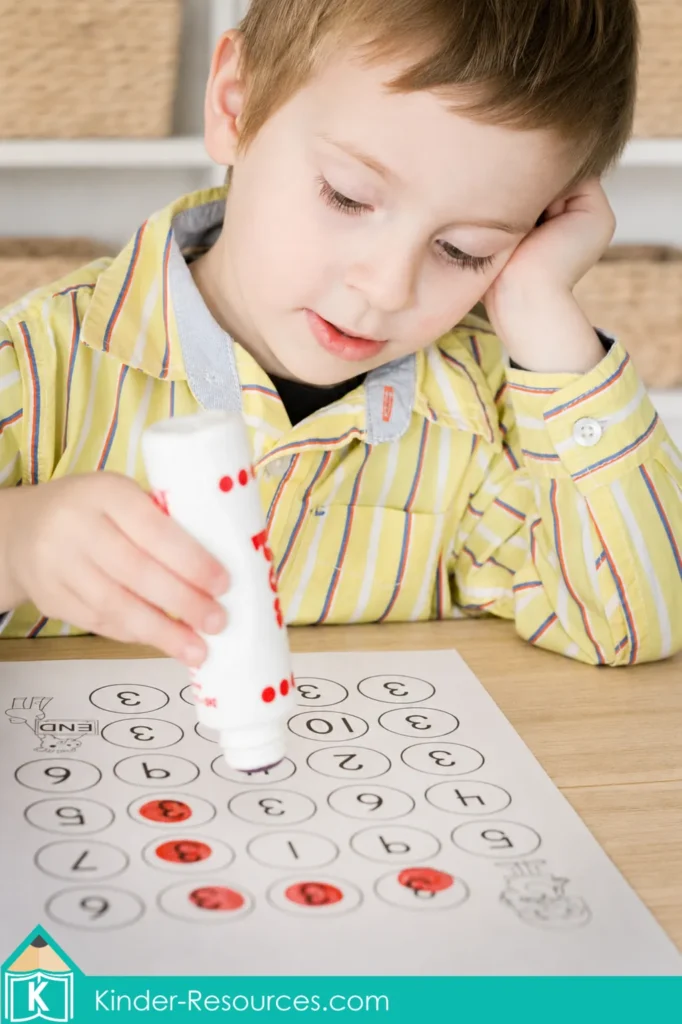 Child using a bingo dauber to find numeral 3 during preschool letter K week number recognition practice.