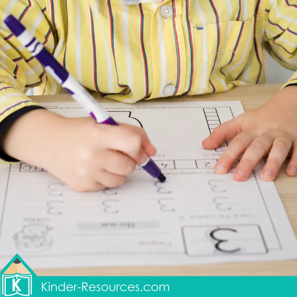 Child tracing and writing numeral 3 with a purple marker during preschool letter K week handwriting and number formation practice.