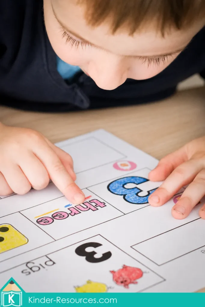 Child matching the numeral 3, number word three, three pigs, and a three-dot die during preschool letter K math activities.