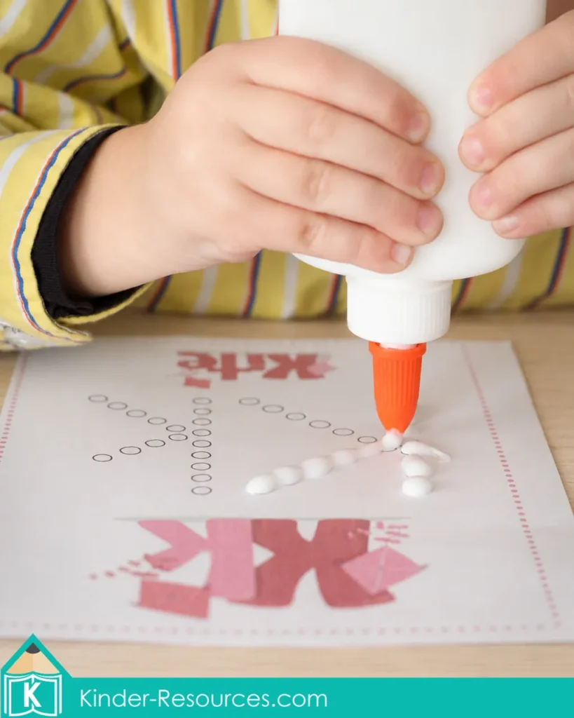 Child squeezing white school glue onto dotted uppercase and lowercase K paths during a preschool letter K fine motor craft activity.