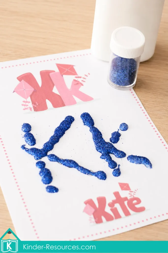 Blue glitter covering dotted uppercase and lowercase K paths during a preschool letter K fine motor and letter formation craft.