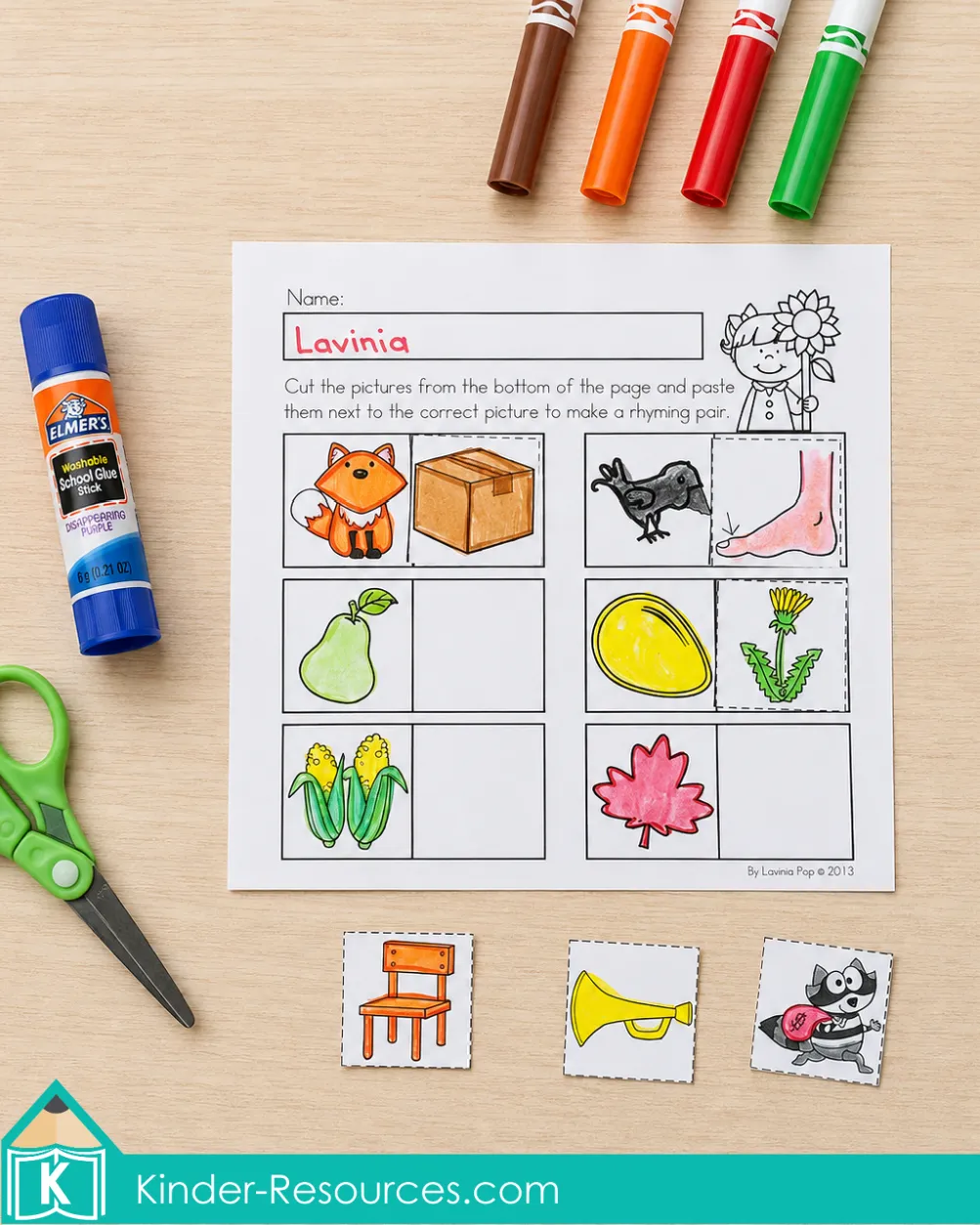 Cutting and pasting pictures beside fall images to create rhyming pairs using an autumn literacy worksheet for kindergarten.