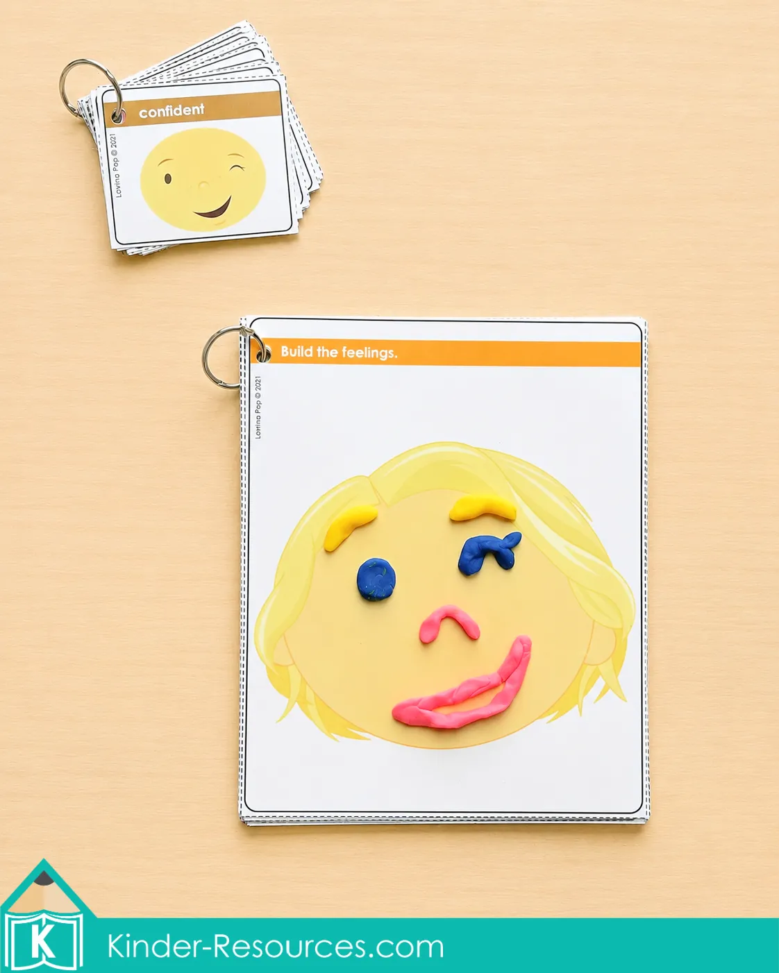 Using playdough to build a confident expression on a printable feelings mat beside emotion vocabulary cards.