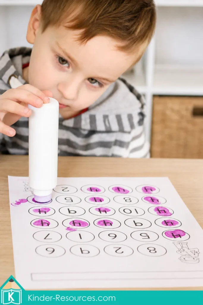 Child using a purple bingo dauber to find numeral 4 among mixed numbers during a preschool number recognition activity.