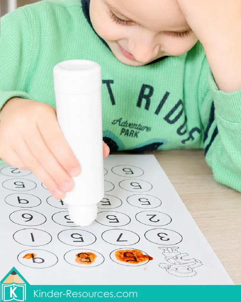 Child using a bingo dauber to find numeral 5 through a preschool number 5 recognition maze worksheet.