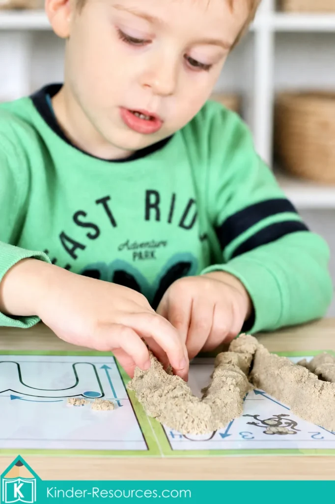 Child pressing crumbly sensory sand along a lowercase m formation mat during preschool Letter M tactile and fine motor practice.