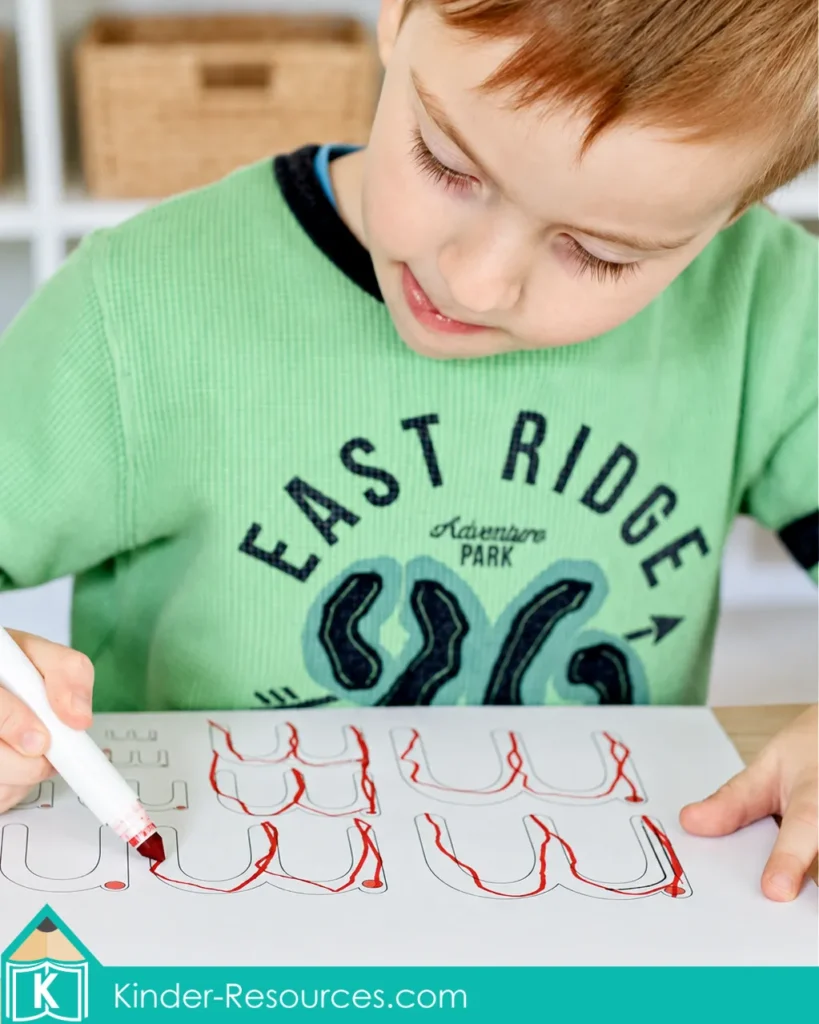 Child tracing lowercase letter M formations with a red marker during a preschool letter M handwriting and fine motor activity.