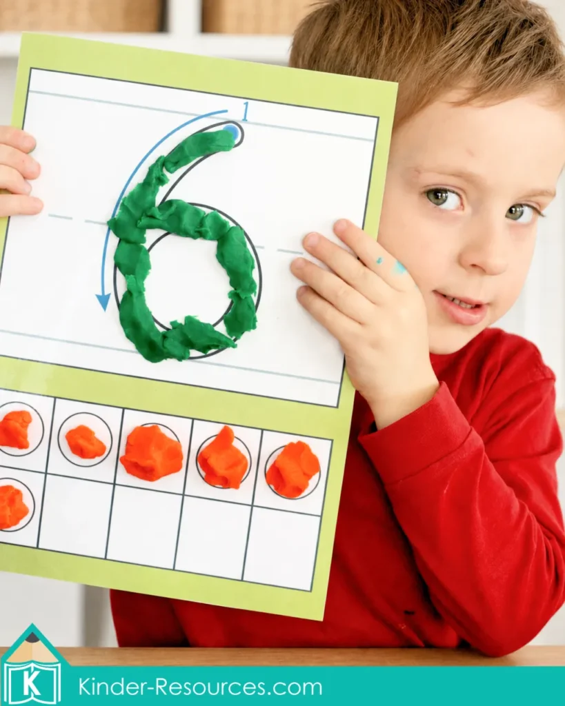 Preschool child showing a number 6 play dough mat with green play dough and six orange counters in a ten-frame.