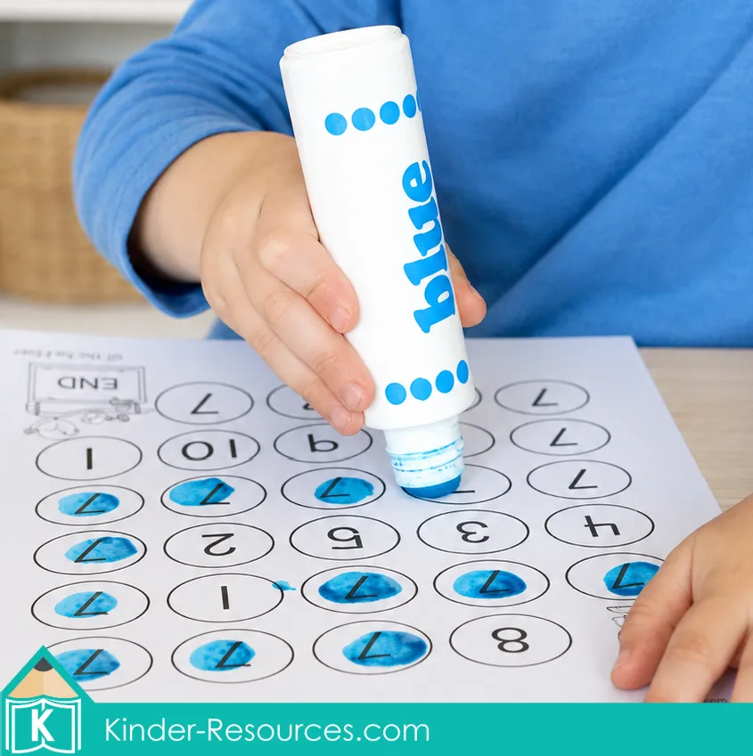 Using a blue dot marker to find and mark the number 7 among other numerals on a printable identification worksheet.