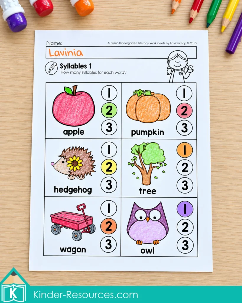 Syllable counting worksheet with colored answers for apple, pumpkin, hedgehog, tree, wagon, and owl.