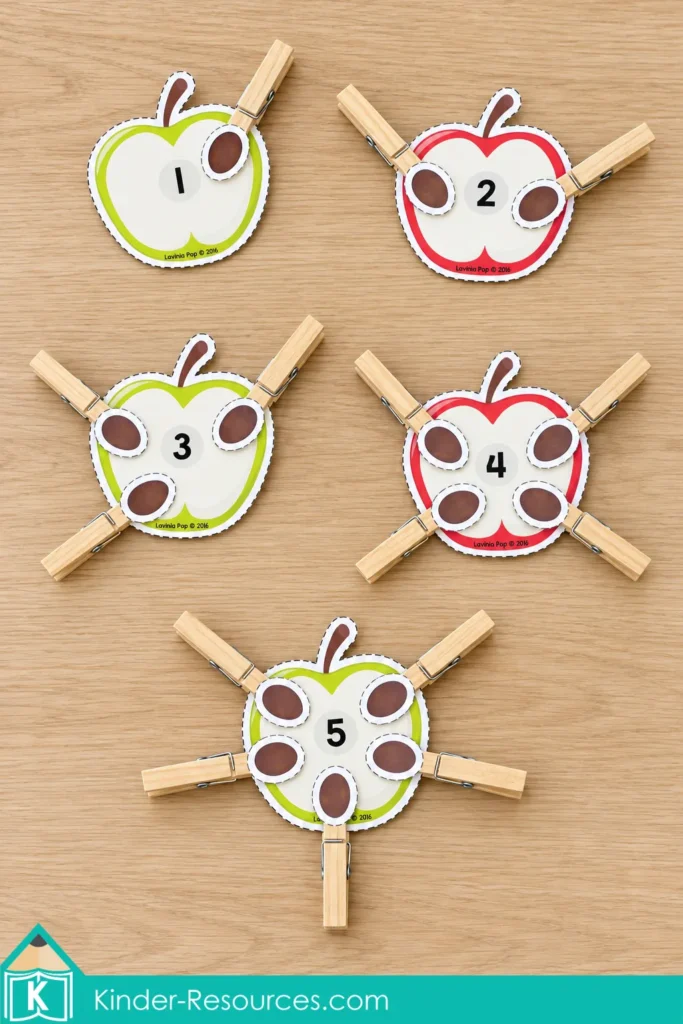 Apple cards numbered 1–5 for fall preschool centers with matching quantities of seed pieces mounted on wooden clothespins.