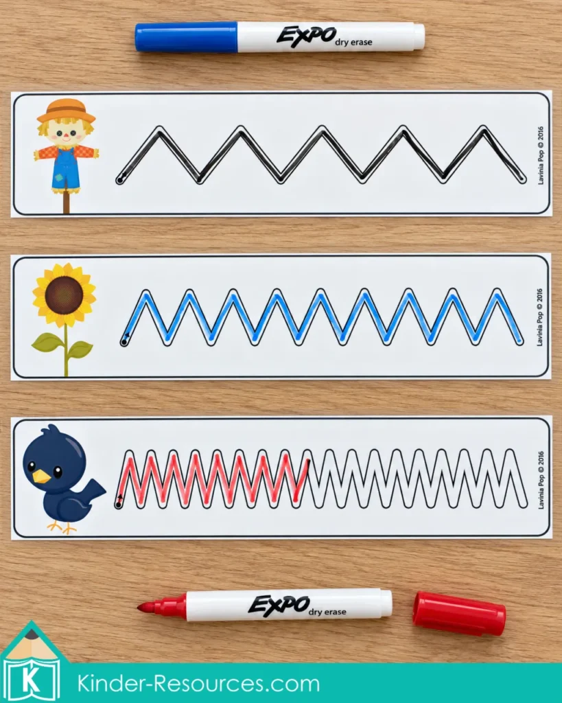 Zigzag tracing cards for fall preschool centers with scarecrow, sunflower, and crow pictures beside blue and red dry-erase markers.