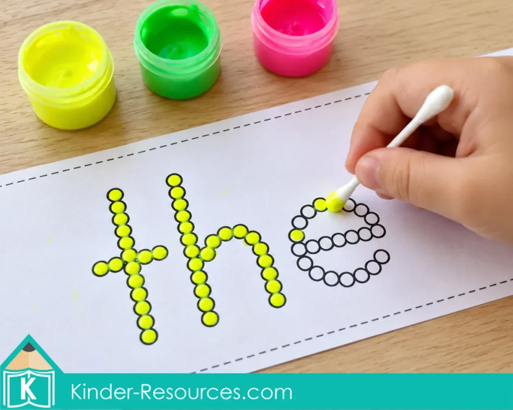 Child using a cotton swab and fluorescent paint to complete the sight word the