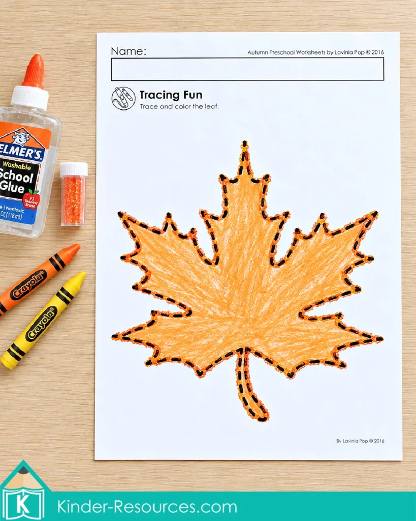 Fall fine motor worksheet with a large maple leaf, a dashed outline for tracing, and orange crayon coloring.