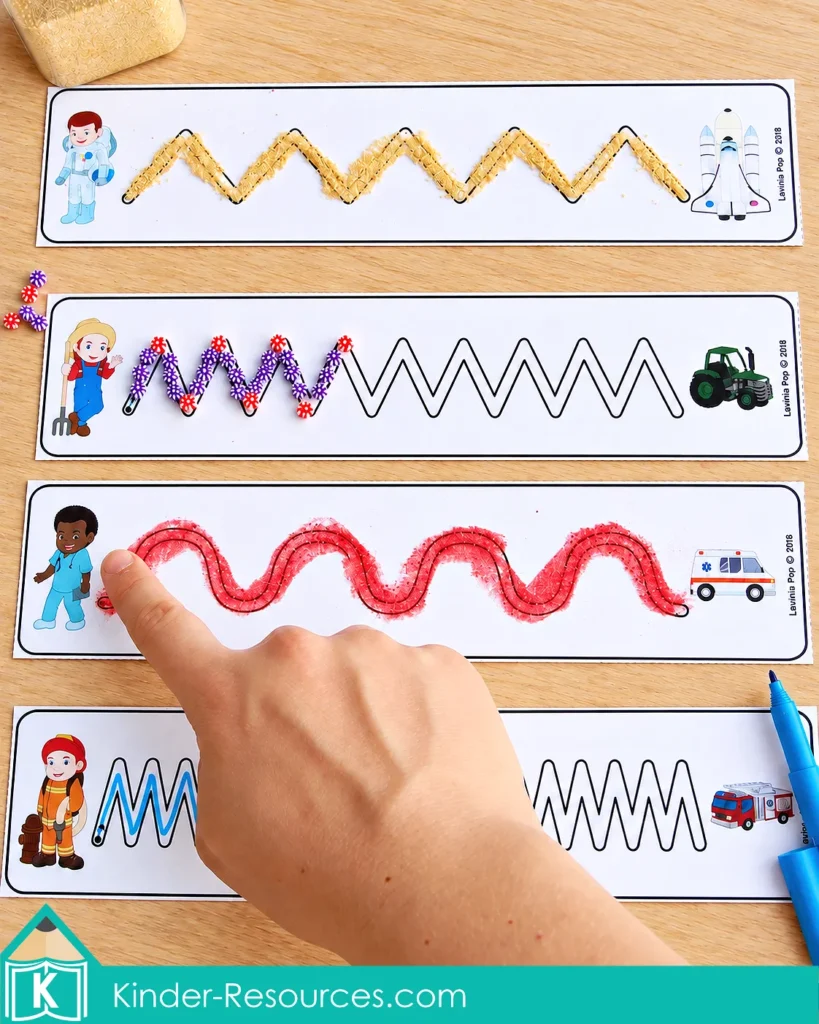 Community helper tracing cards with paths covered in sand, beads, glitter glue, and marker, with a finger following the wavy glitter glue line.