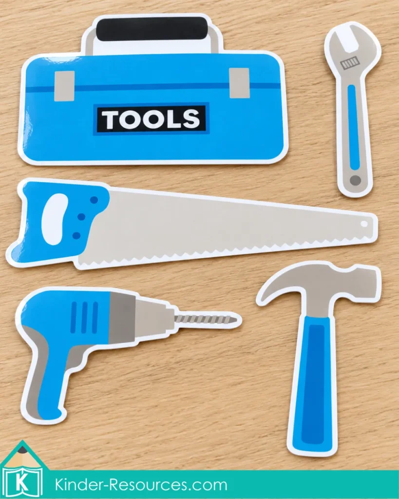 Blue toolbox with matching blue and gray wrench, saw, drill, and hammer pieces arranged on a wooden table.